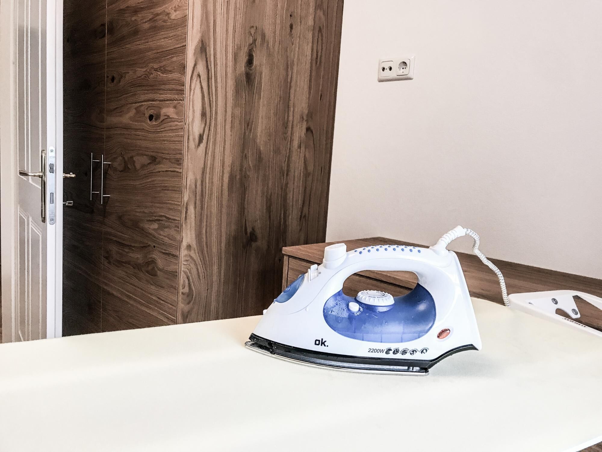 An iron on a white table in a room with wooden flooring and a white wall.