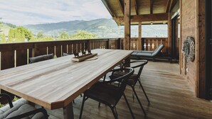 A wooden deck with a table and chairs, overlooking a mountainous landscape. - First IN Mountain Chalet B (Kaprun)