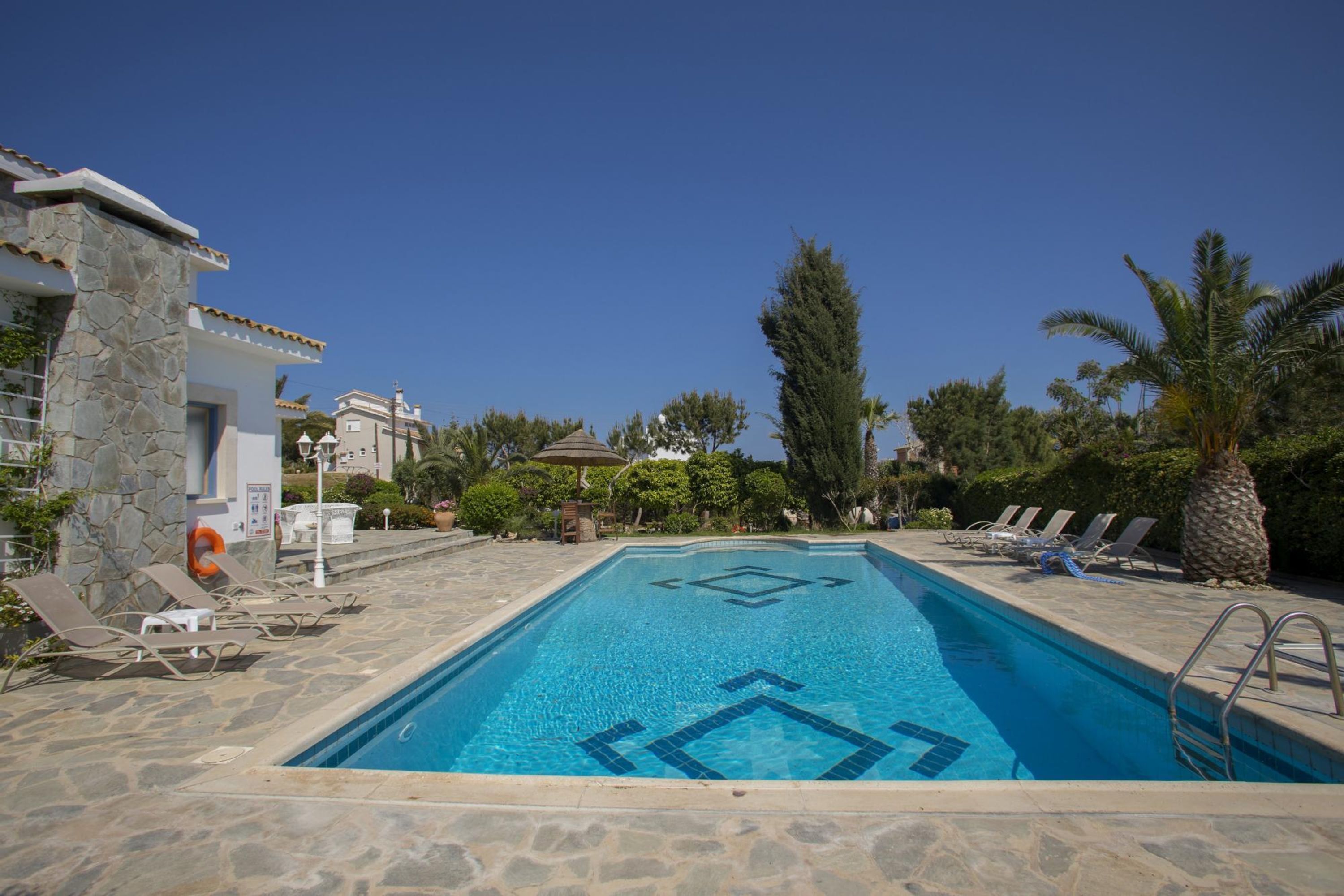 A swimming pool with lounge chairs and a stone wall.