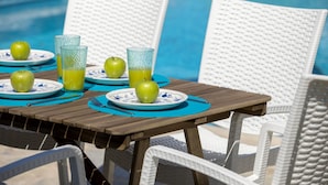 A poolside table with plates of green apples and glasses of orange juice, surrounded by white wicker chairs. - Mazeri in Protaras With 5 Bedrooms and 4 Bathrooms (Ayia Napa)