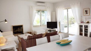 Ein modernes Wohnzimmer mit einem weißen Sofa, einem gestreiften Sessel und einem Esstisch mit einer blauen Schüssel.