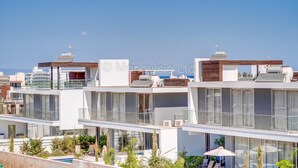 A modern residential building with multiple balconies, large windows, and solar panels. - Protaras Olivine Pearl Villa 16 (Paralimni)