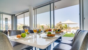 A dining area with a table set for breakfast, featuring plates with croissants, apples, and glasses of orange juice. - Protaras Olivine Pearl Villa 16 (Paralimni)