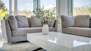 A modern living room with a grey sofa, a white marble coffee table, and a vase with flowers. - Protaras Olivine Pearl Villa 16 (Paralimni)