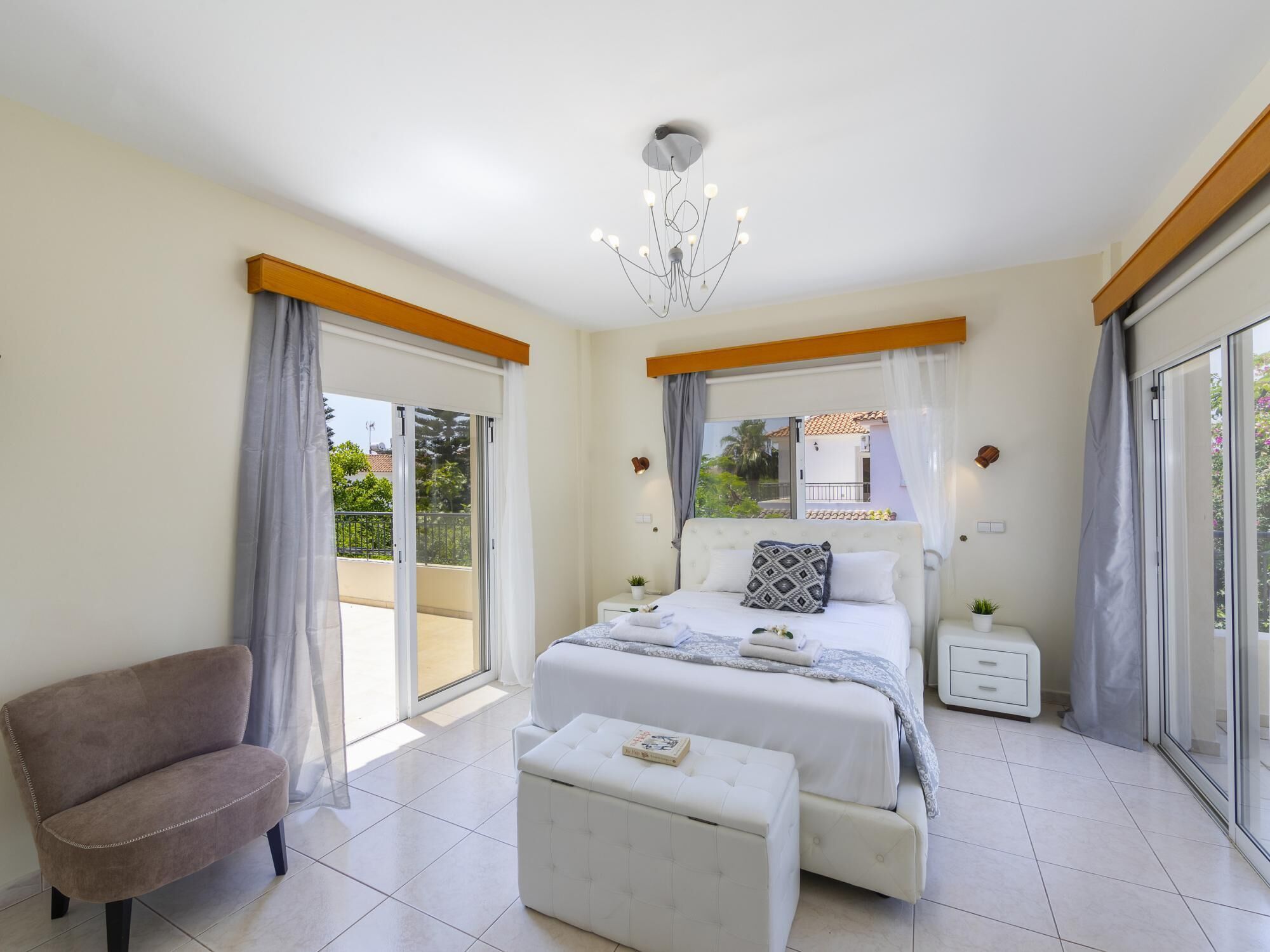 A bedroom with a bed, a sofa, a small table, and a balcony.