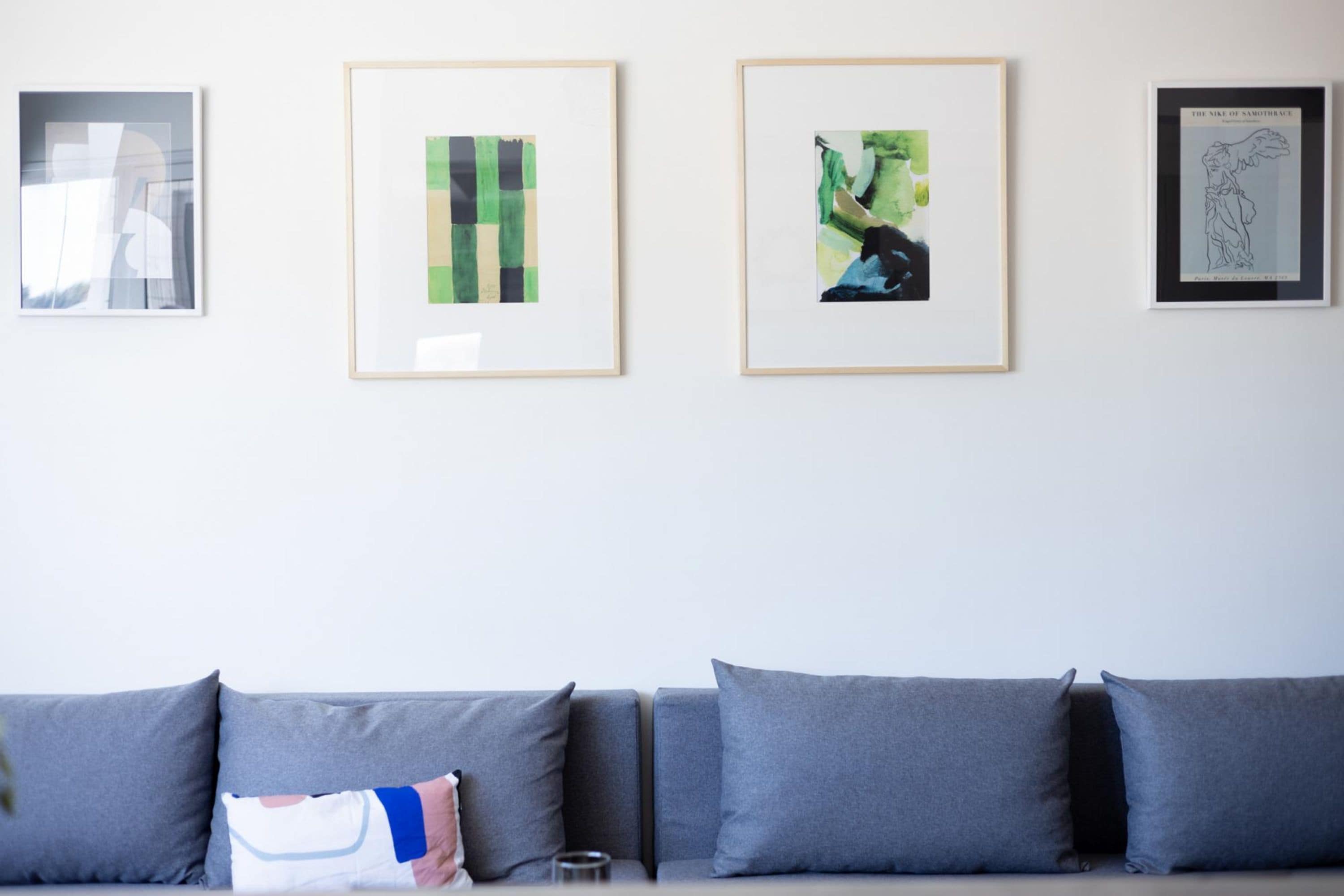 A modern living room with a grey sofa and three framed artworks on the wall.