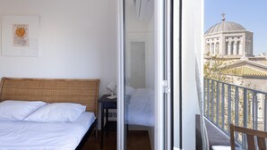 A hotel room with a bed, a small desk, and a balcony with a view of a building. - 3 Bdrm Luxury Apt Incredible Acropolis View (Athens)