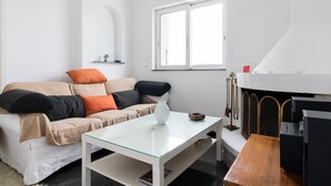 Uma sala de estar moderna com um sofá branco, uma mesa de centro de vidro e uma lareira.