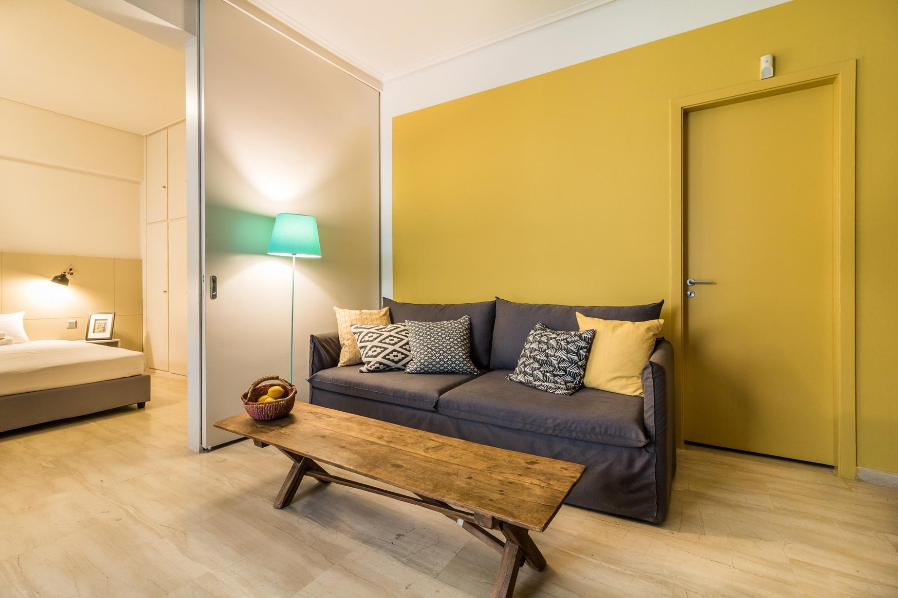 Una sala moderna con un sofá, una mesa de centro de madera, una lámpara de pie y una cama.