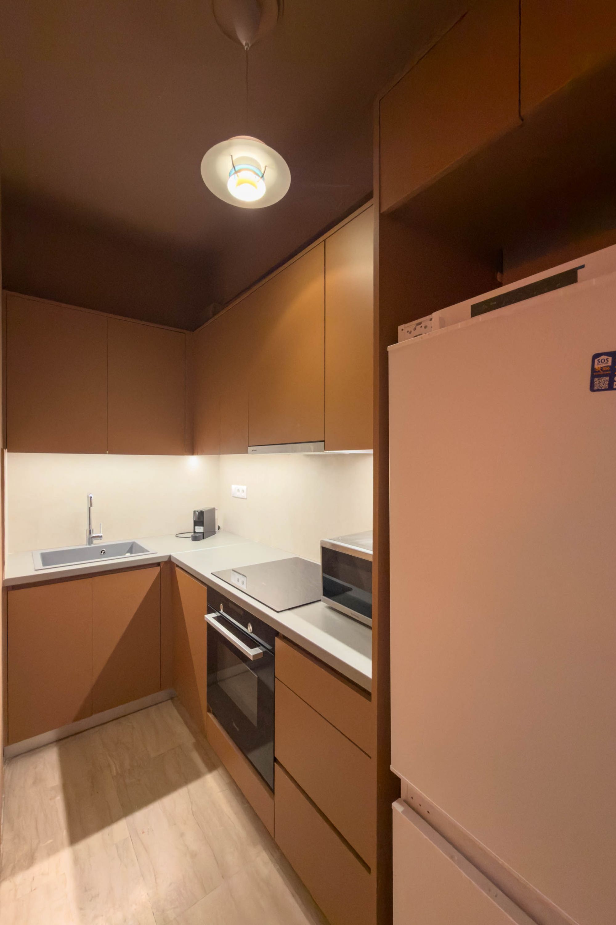 A compact kitchen with a sink, oven, and a refrigerator.