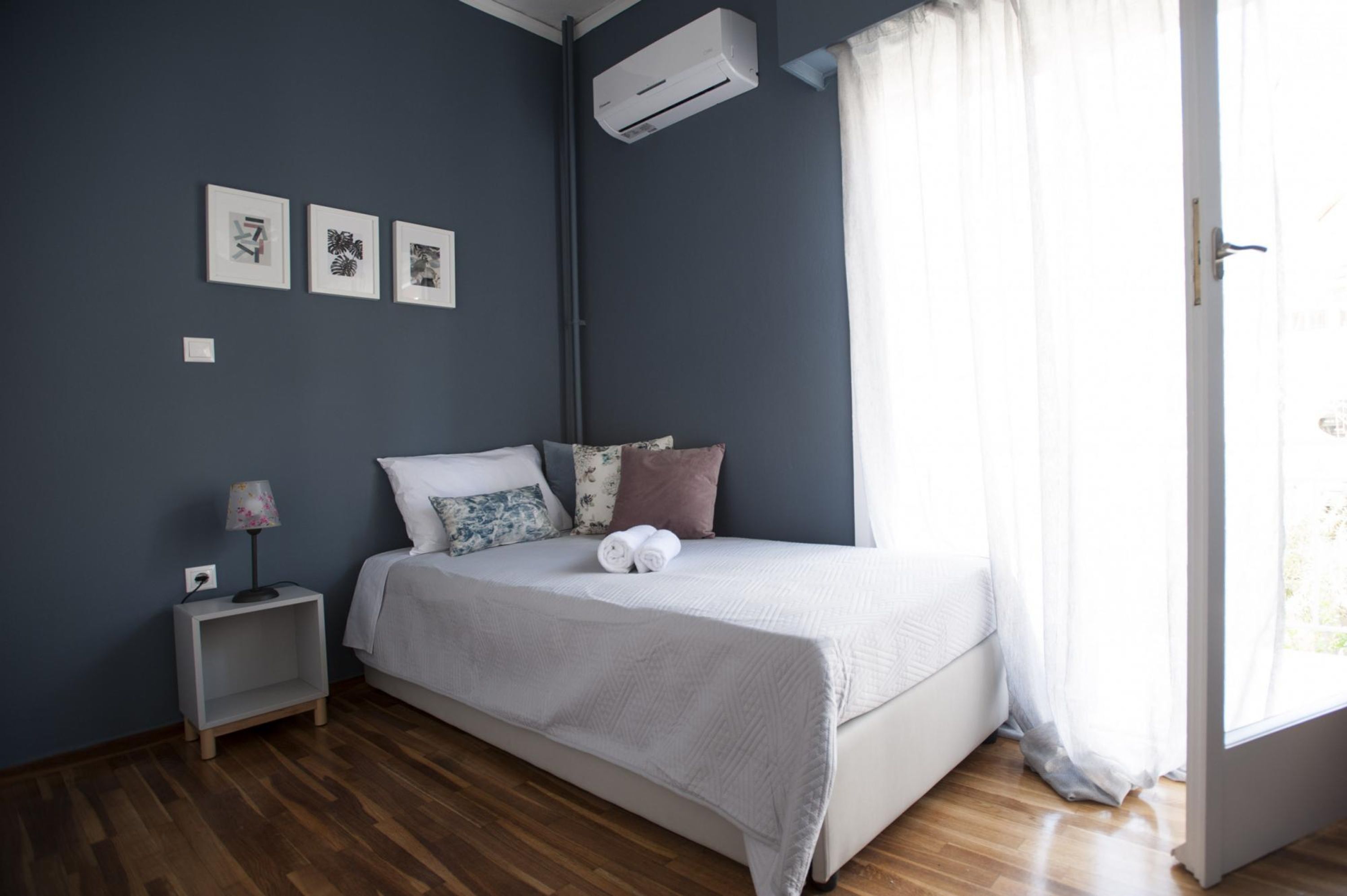 Une chambre à coucher avec un lit, une table de chevet, une lampe et trois tableaux encadrés accrochés au mur.