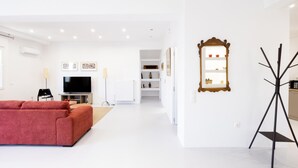 A modern living room with a red sofa, a TV, and framed pictures on the wall. - Beautiful 2 Bdrm apt in Athens (Athens)