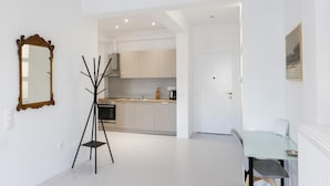 A modern kitchen with white cabinets, a dining area with a glass table, and a standing lamp. - Beautiful 2 Bdrm apt in Athens (Athens)