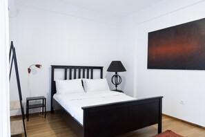 A bedroom with a bed, a nightstand, a lamp, and a painting on the wall. - Beautiful 2 Bdrm apt in Athens (Athens)