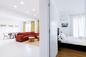 A modern living room with a red sofa, a dining table, and a kitchen area. - Beautiful 2 Bdrm apt in Athens (Athens)