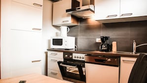 A compact kitchen with a microwave, coffee maker, and oven. - Apartment Bauernhof Birkh fl - TOP 1 (Zell am See)