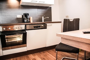 A modern kitchen with a built-in oven, a coffee maker, and a wooden dining table.