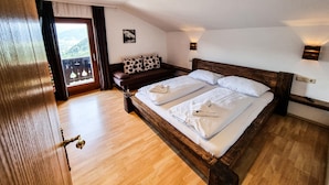 A bedroom with a wooden bed, a sofa, and a view through a window. - Apartment Bauernhof Birkh fl - TOP 1 (Zell am See)