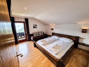 A bedroom with a wooden bed, a sofa, and a view through a window.