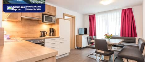 A modern kitchen with a microwave, coffee maker, and a dining area with a table and chairs.