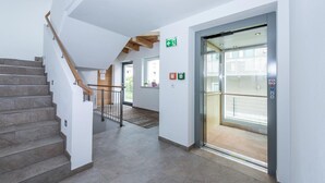A modern interior with a staircase, an elevator, and a hallway. - Appartements Sulzer - TOP 15 (Zell am See)