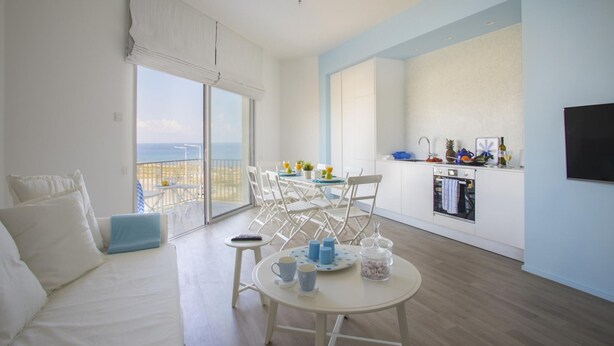 Un amplio espacio habitable con balcón, una mesa de comedor y una zona de cocina.