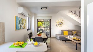 A modern kitchen with a dining area, a staircase, and a living room with a sofa and coffee table. - Protaras Villa Angela Nefeli (Paralimni)