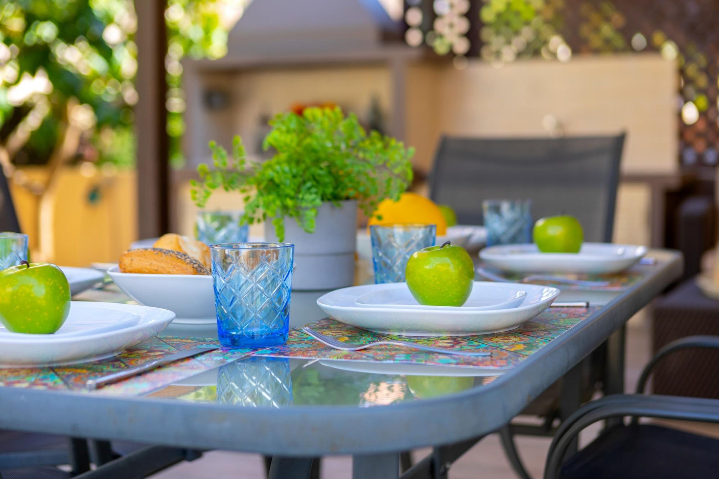 A dining table set with plates, glasses, and a potted plant.