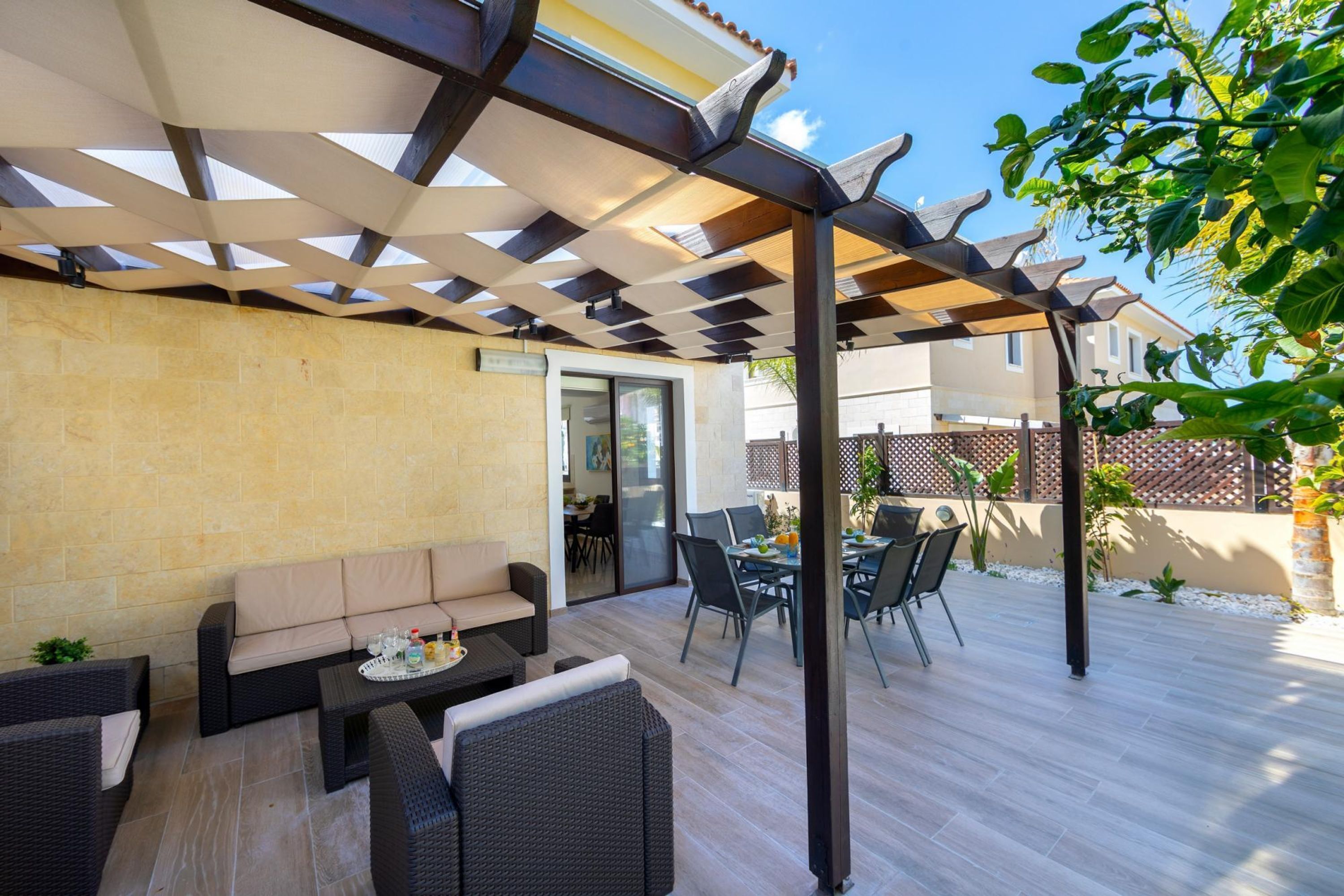 An outdoor patio with a covered seating area, a dining table, and chairs.