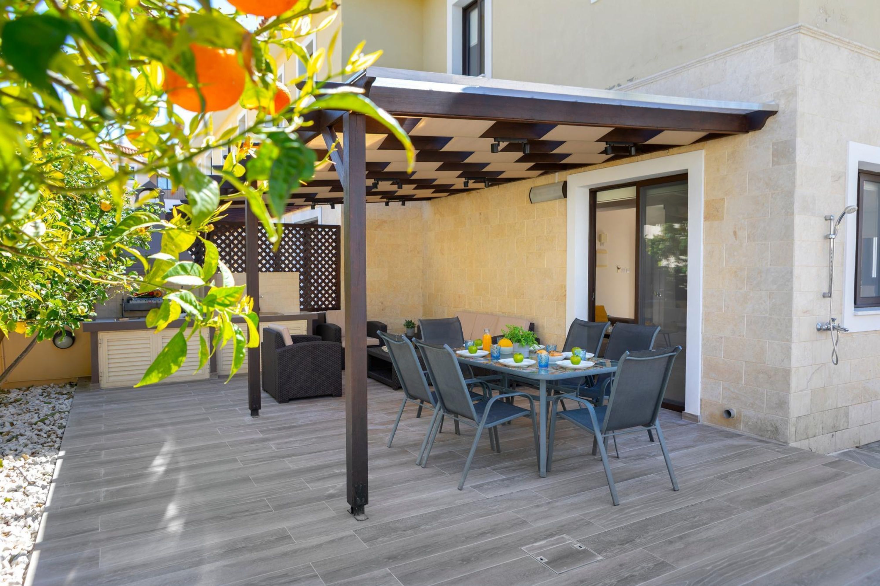 An outdoor patio with a table and chairs, a pergola, and a covered area.