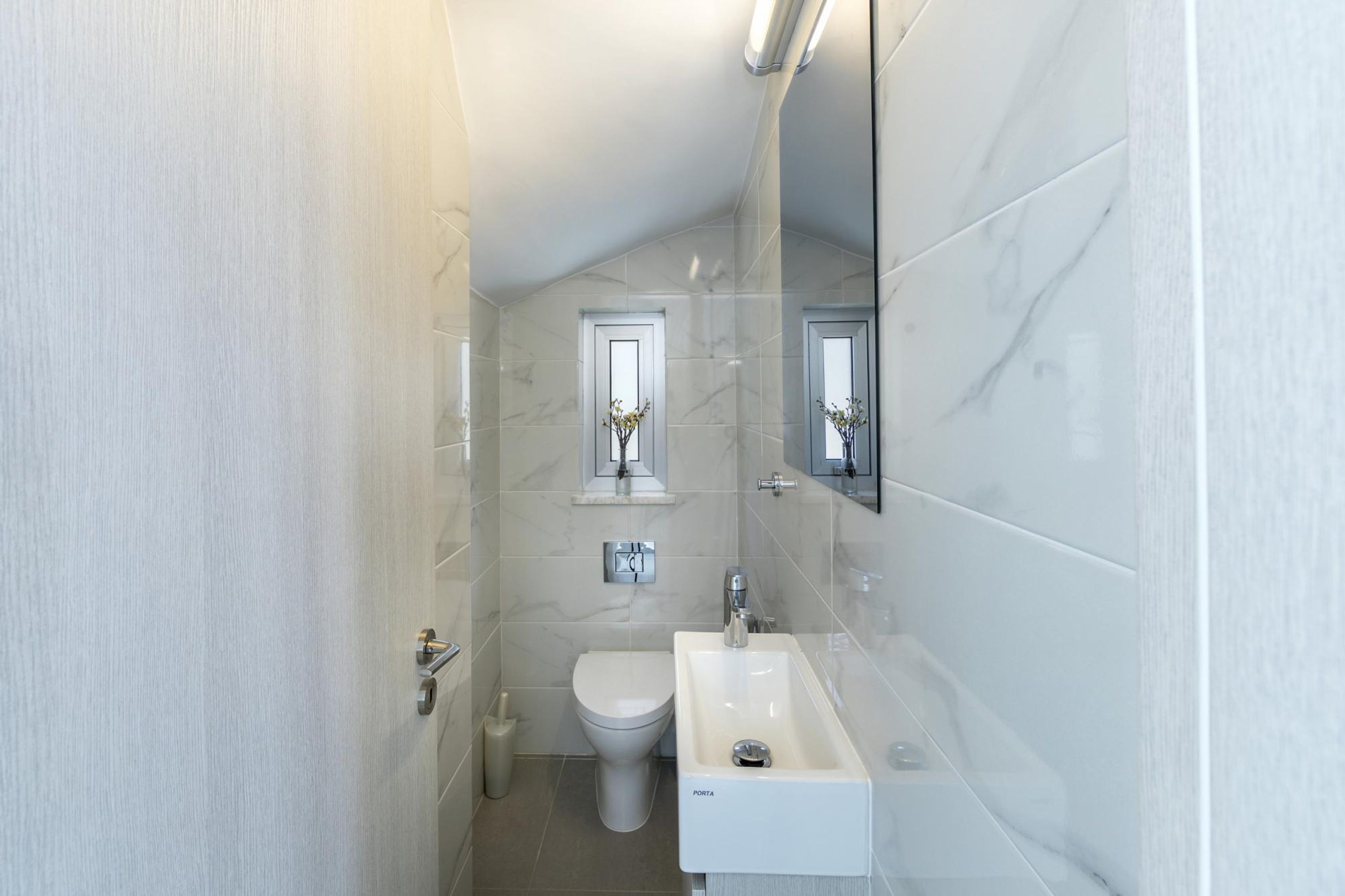 A compact bathroom with a toilet, sink, and mirror.