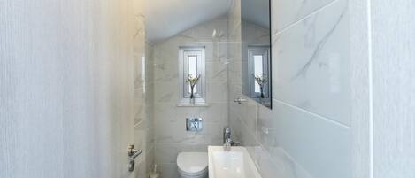 A compact bathroom with a toilet, sink, and mirror.