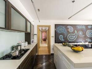 Une cuisine moderne dotée d’un îlot central, d’un four à micro-ondes, d’une cuisinière et d’un grand élément décoratif mural.