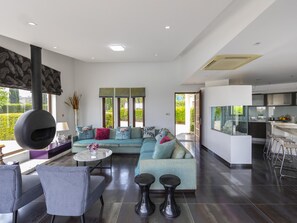 Uma sala de estar moderna com um sofá grande, uma mesa de jantar e uma cozinha.