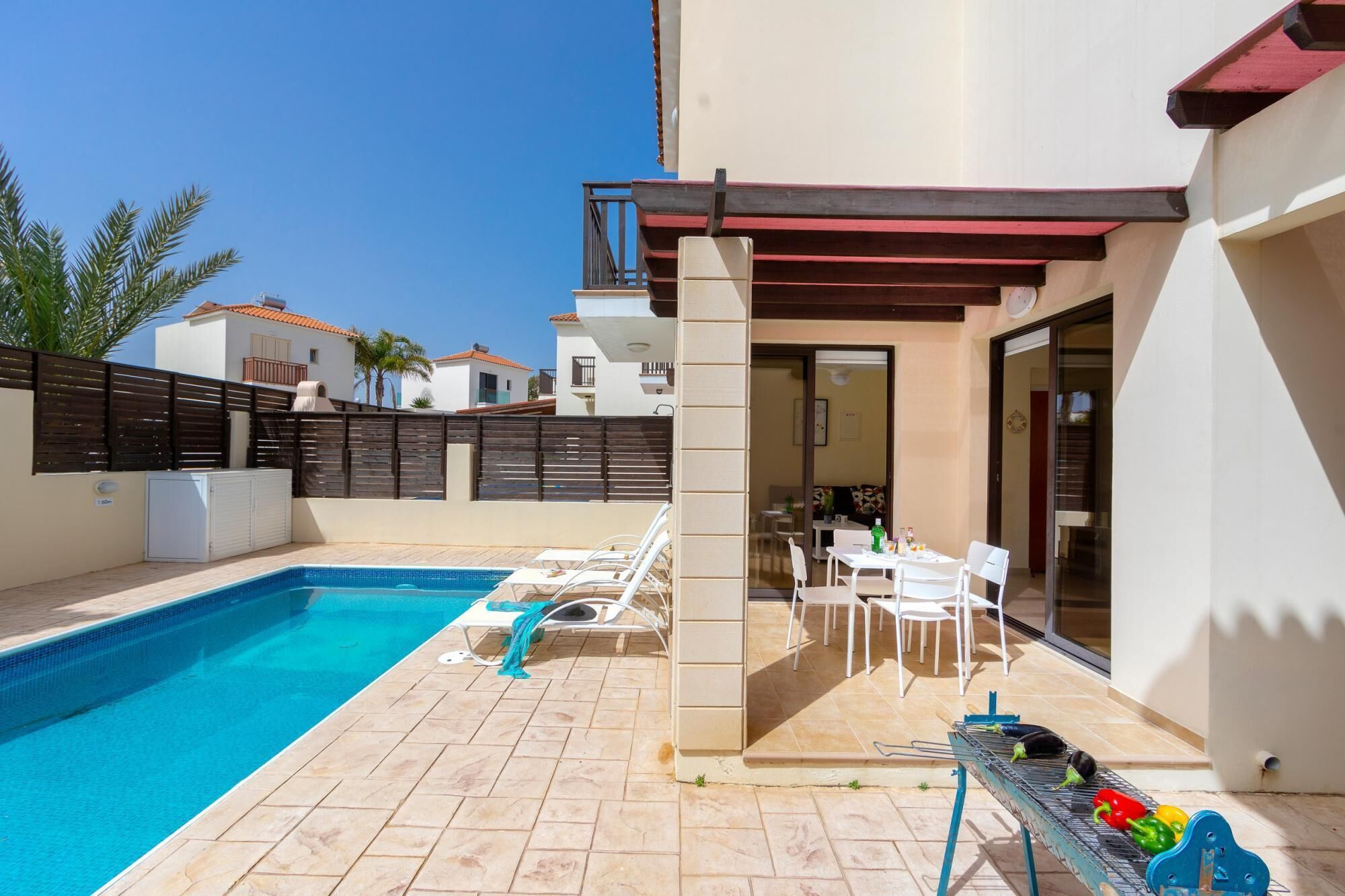 A poolside area with a pool, lounge chairs, a barbecue grill, and a patio table.