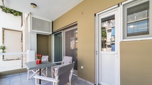 Ein Balkon mit Tisch und Stühlen, einer Schiebetür und Blick auf die Straße.