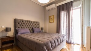Ein Schlafzimmer mit einem großen Bett, einem Nachttisch, einer Lampe und einem Fenster mit Vorhängen.