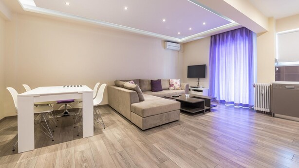 Een moderne woonkamer met een bank, een eettafel en een televisie.