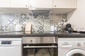 A kitchen with a stainless steel range hood, a coffee maker, a toaster, and a washing machine. - Bright 2 Bdrm apt in the Heart of Athens (Athens)