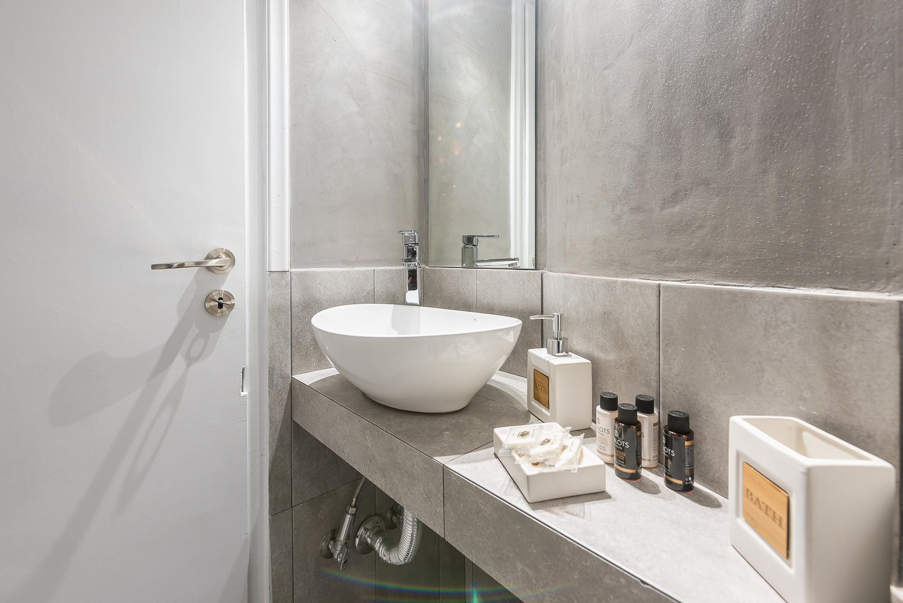 A modern bathroom with a large white sink, a mirror, and a towel rack.