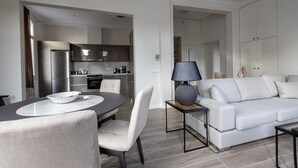 A modern living room with a dining area, a sofa, and a kitchen visible through an open doorway. - Plaka s Privileged Accommodation (Athens)