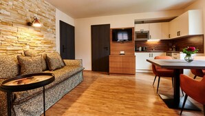 Un salon moderne avec un mur en pierre, un canapé, une table basse et un coin repas comprenant une table et des chaises.