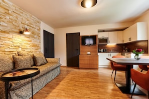 A modern living room with a stone wall, a sofa, a coffee table, and a dining area with a table and chairs.