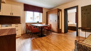 Une cuisine moderne avec des meubles en bois, un coin repas comprenant une table et des chaises, et une vue sur l’extérieur par une fenêtre.