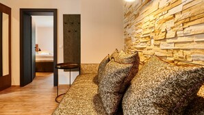 Un salon moderne avec un mur en pierre, un canapé agrémenté de coussins à motifs et une petite table.