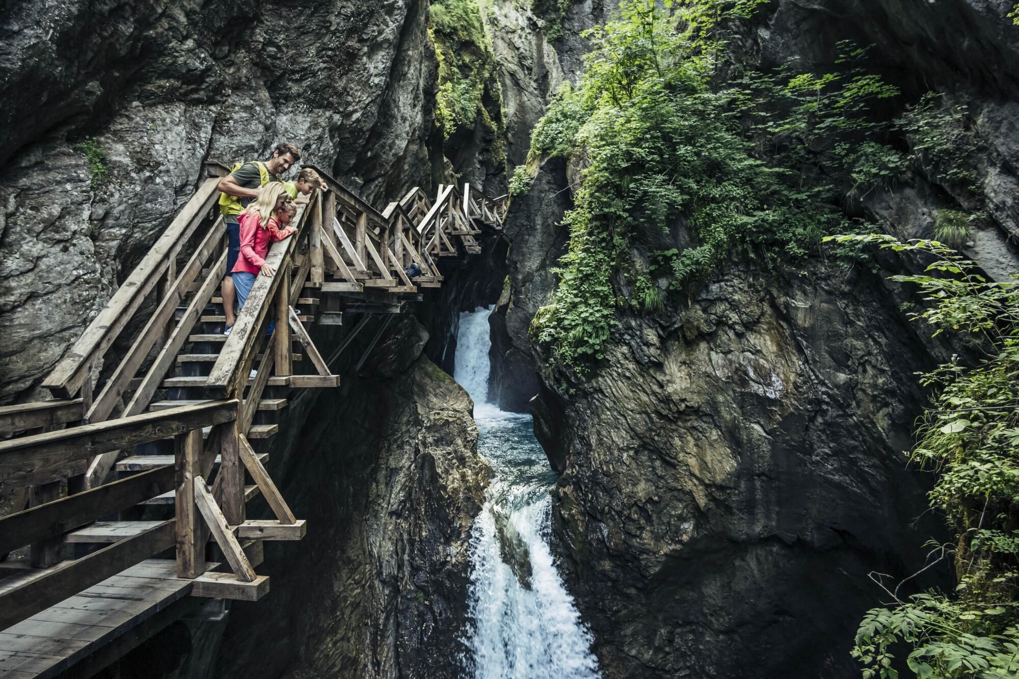 Een houten brug boven een waterval in een rotsachtige kloof.