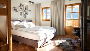 Ein Hotelzimmer mit einem Bett, einem Holzstuhl, einem Hund und einem Fenster mit Vorhängen.