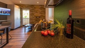 Una cocina moderna con salpicadero de piedra, un comedor con mesa y sillas, y un televisor al fondo.