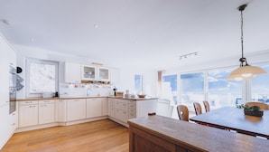 Una cucina moderna con mobili in legno, un tavolo da pranzo in legno e un'ampia finestra con vista sulle montagne.