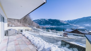 Patio moderno all'aperto con vista su un lago e montagne.